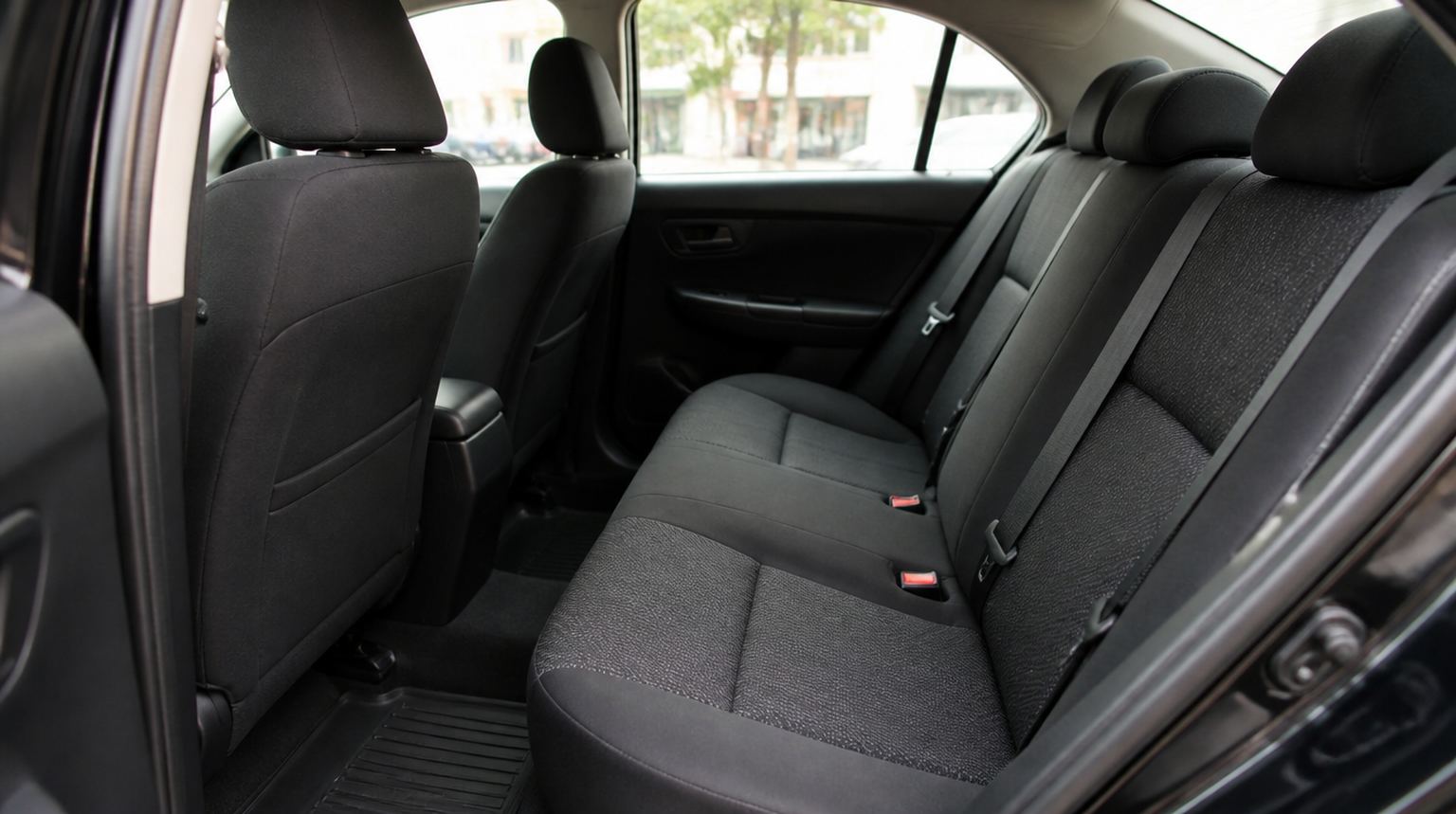Clean rear seats of a Payless Taxi sedan viewed through the open rear door