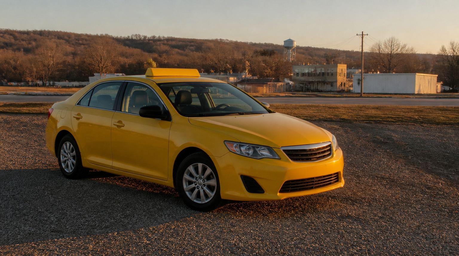 Yellow taxi parked on a gravel lot at sunrise on the edge of a small western Arkansas town